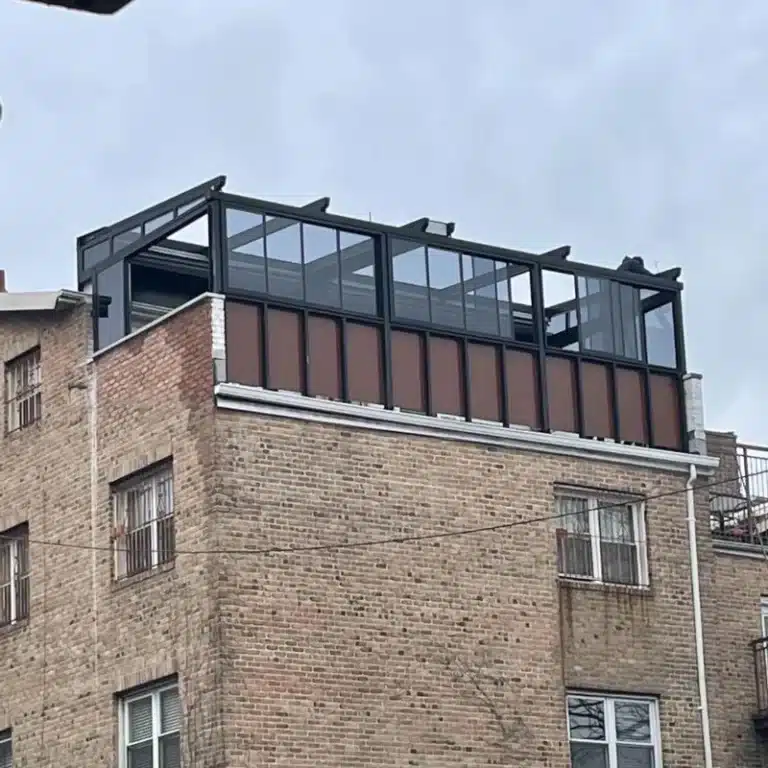 A building featuring a glass roof, surrounded by blue sky and clouds, showcasing a modern architectural design with brick facade and large windows.